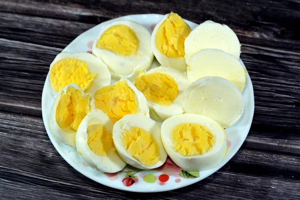 Haşlanmış yumurta dilimleri önceden kaynamış suda pişirilir, parçalara ayrılır ve küçük bir tabakta servis edilir. Ahşap bir arka planda izole edilir. Kahvaltıda iyi bir atıştırmalık ve gündüz vakti.