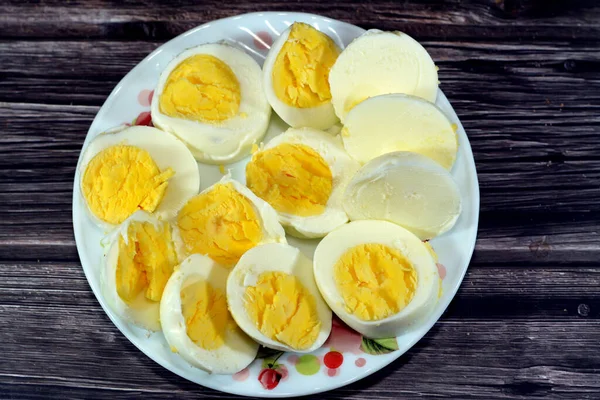 Haşlanmış yumurta dilimleri önceden kaynamış suda pişirilir, parçalara ayrılır ve küçük bir tabakta servis edilir. Ahşap bir arka planda izole edilir. Kahvaltıda iyi bir atıştırmalık ve gündüz vakti.