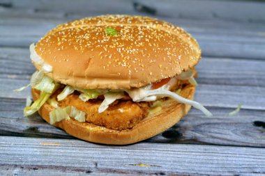 Özel soslu leziz tavuk köftesi, iki taze domates dilimi, çıtır marul, iki dilim İsviçre peyniri ve bir parça tavuk rulosu büyük bir çörek, tavuklu sandviç, seçici odaklanma.