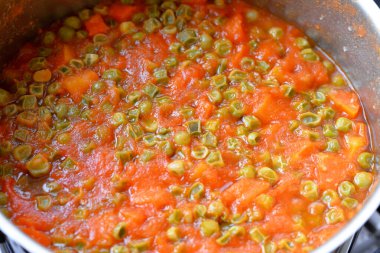 A vitamini, C vitamini, biraz kalsiyum minerali ve bağışıklık sisteminizi güçlendiren antioksidan ve yüksek fiber içerik içeren domates soslu pişmiş havuç ve bezelye dilimleri.