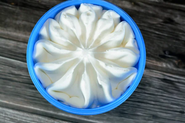 木製の背景に隔離されたプラスチック製のボウルにバニラホワイト冷凍アイスクリームを提供する準備ができて 青い容器の花の形をしたバニラアイス 選択的な焦点 — ストック写真