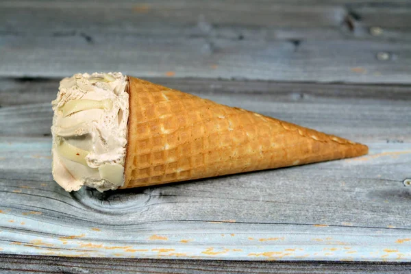 クリスピーなウェーハコーンの中の特別な味のアイスクリーム 木製の背景 夏と休日のコンセプト 選択的な焦点に隔離されたウェーハビスケットで冷たいアイスクリームの小枝を溶かす — ストック写真
