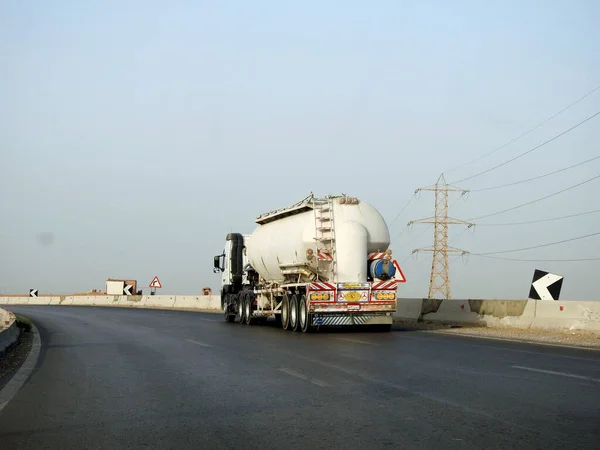 stock image Cairo, Egypt, May 20 2023: A big truck with a container tank with petroleum products, a lorry on the highway with a container on it delivering the products for industrial usage, selective focus