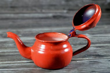 Antika eski usul çaydanlık, ahşap zemin üzerinde izole edilmiş kırmızı çay demliği, saplı çay yapmak ve servis etmek için bir kap ve dökmek için şekilli bir açıklık, seçici odaklanma için