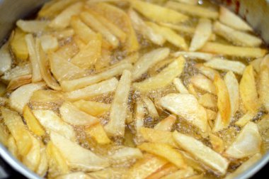 Evdeki fritözde kızgın yağda kızartılmış patates kızartması. Patates kızartması, abur cubur konsepti, ev yapımı kızarmış cips, seçici odaklanma.
