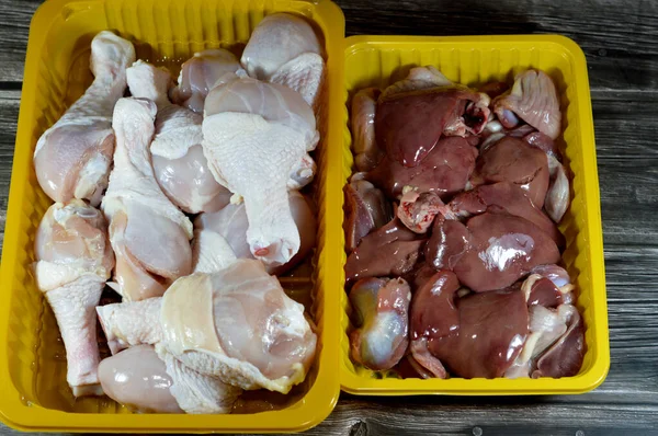 Raw chicken legs drumsticks hindquarter with skin and bones and fresh uncooked chicken livers, gizzards and hearts, selective focus of fresh liver, gizzard and heart of chickens full of protein