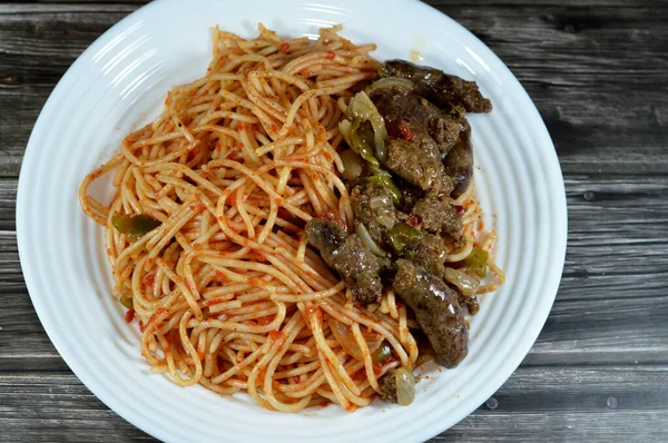 stock image A plate of Middle Eastern cooked beef sausage, Egyptian sausages with green peppers, onion, garlic, tomato, black pepper and oil and classic spaghetti pasta macaroni with tomato sauce, selective focus