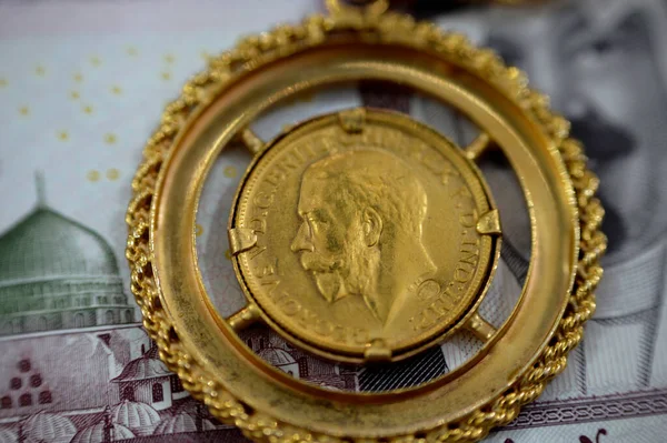 sovereign British gold coin shapes bullion coin features George and dragon Jewellery or jewelry on Saudi Arabia riyals cash money banknote, Gold price in Egypt pound and inflation concept