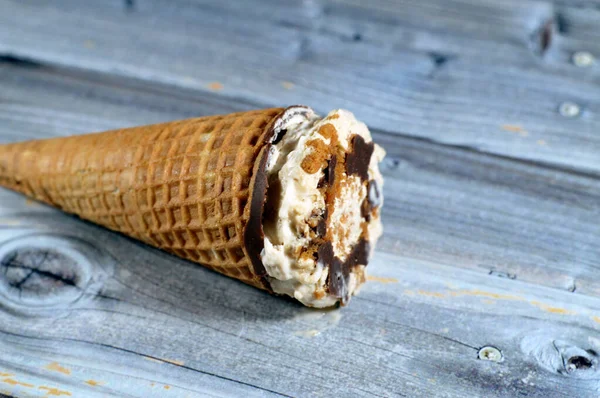 キャラメル化されたビスケットココアチョコレートとバニラコーンのアイスクリームは ビスケットピースとナッツをクリスピーなウエハーコーンにトッピングし ウエハービスケットで冷たいアイスクリームの小枝を溶かし 夏休みのコンセプト — ストック写真