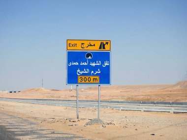 Kenardaki trafik levhasındaki Arapça metnin çevirisi (Şehit Ahmed Hamdy Tüneli Çıkışı, 300 metre ilerideki Sharm El Sheikh şehri) Ahmad Hamdi tüneli ve Sharm Al Sheikh şehir yönü