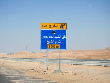 Kenardaki trafik levhasındaki Arapça metnin çevirisi (Şehit Ahmed Hamdy Tüneli Çıkışı, 300 metre ilerideki Sharm El Sheikh şehri) Ahmad Hamdi tüneli ve Sharm Al Sheikh şehir yönü