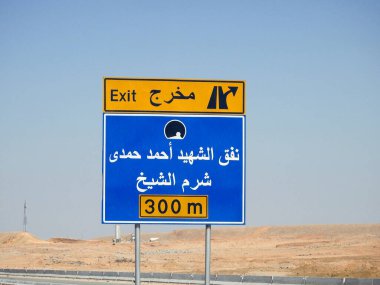 Kenardaki trafik levhasındaki Arapça metnin çevirisi (Şehit Ahmed Hamdy Tüneli Çıkışı, 300 metre ilerideki Sharm El Sheikh şehri) Ahmad Hamdi tüneli ve Sharm Al Sheikh şehir yönü