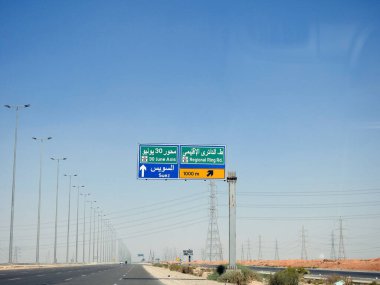 Kahire, Mısır, 30 Haziran 2023: Süveyş Kahire Çölü karayolu üzerindeki bilgilendirici yan trafik levhası 30 Haziran Mihver ve Süveyş kentlerinde bölgesel çevre yolunun yönlerini gösteriyor.