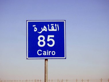 Kahire otobanındaki bir yol tabelası Kahire şehrine kalan mesafeyi İngilizce ve Arapça sözcüklerle Kahire yakınlarında yazılmış 85 KM 'lik bir yol tabelası veriyor.