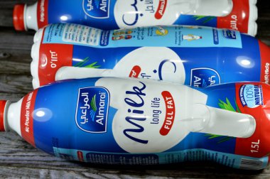 Kahire, Mısır, 26 Haziran 2023: Almarai tam yağlı kremalı süt 1,5 litrelik koruyucu madde ve D vitamini içermeyen konteynır, ahşap zeminde izole edilmiş doğal süt