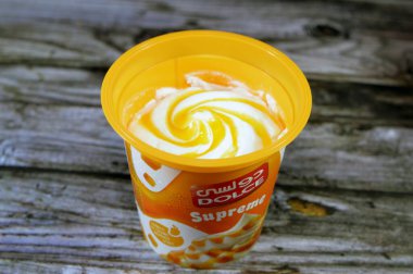 Kahire, Mısır, 6 Temmuz 2023: Dolce Supreme dondurması mango ya da çilek sosu gibi meyve soslu dondurulmuş vanilya, DOLCE dondurmalı Mısır ürünleri ahşap arka planda izole edilmiş tatlar