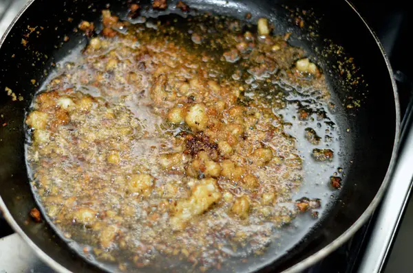 preparing the last step of the popular Egyptian Molokhiya soup making Taqliya Takliya which is frying minced garlic in ghee with minced coriander seeds and salt in a pan, selective focus