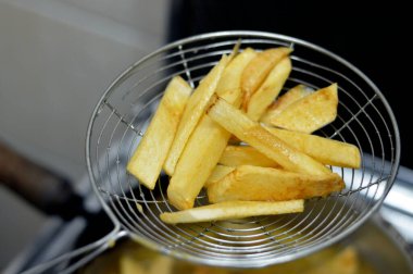 Evdeki fritözde kızgın yağda kızartılmış patates kızartması yakın. Patates kızartması, abur cubur konsepti, ev yapımı kızarmış cips, seçici odaklanma.