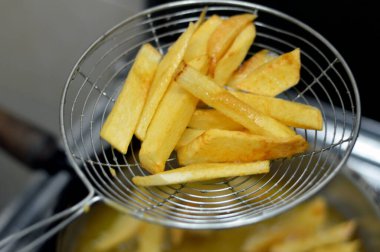 Evdeki fritözde kızgın yağda kızartılmış patates kızartması yakın. Patates kızartması, abur cubur konsepti, ev yapımı kızarmış cips, seçici odaklanma.