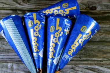 Kahire, Mısır, 15 Temmuz 2023: Kimo Kono Nestle vanilyalı dondurma üzerine karamelli, fındıklı ve çikolata parçacıklı gofretli gofret konileri, dondurmalı bisküvilerin içinde eriyen soğuk dondurma