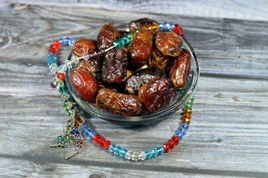 Ramazan arkaplanı, Ajwa tarihleri, Medine, Suudi Arabistan 'da yaygın olarak yetişen palmiye ağacının bir ekini, oval biçimli, orta büyüklükte bir tarih ve 99 boncuklu bir İslami kristal ve gümüş tespih.
