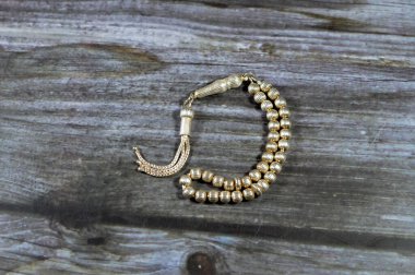 Tahta arka planda 33 tespih ile gümüş renkli İslami küçük tespih, Müslümanlar Allah 'ı övmek için kullanırlar. Allah' ı anmak için cümleler kurarlar.