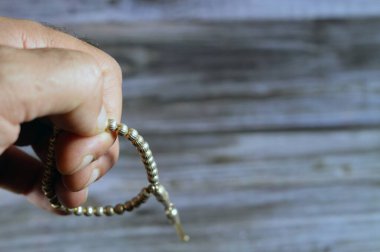Tahta arka planda 33 tespih ile gümüş renkli İslami küçük tespih, Müslümanlar Allah 'ı övmek için kullanırlar. Allah' ı anmak için cümleler kurarlar.