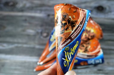 Kahire, Mısır, 27 Temmuz 2023: Ekstrem Nestle çikolatalı dondurma külahı üzerinde çikolata sosu ve çikolatalı kek parçaları gevrek bir gofret külahında erimiş soğuk dondurmalı bisküvi