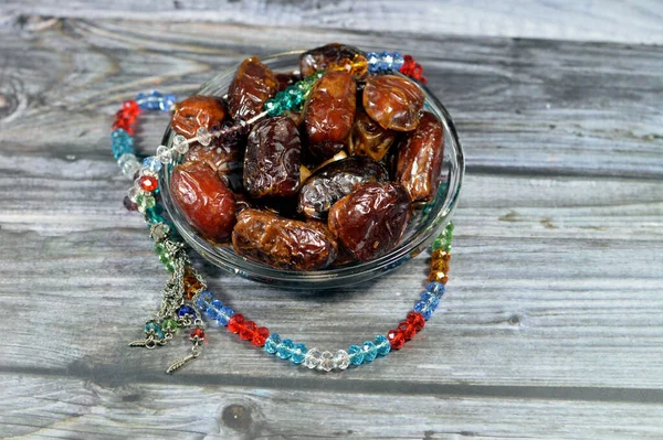 Ramadan background, Ajwa dates, a cultivar of the palm date that is widely grown in Medina, Saudi Arabia., an oval-shaped, medium-sized date, and an Islamic crystal and silver rosary with 99 beads
