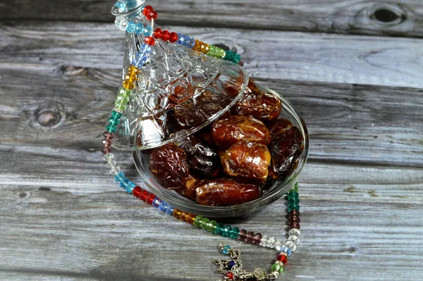 Ramadan background, Ajwa dates, a cultivar of the palm date that is widely grown in Medina, Saudi Arabia., an oval-shaped, medium-sized date, and an Islamic crystal and silver rosary with 99 beads