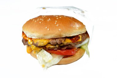 Sosu peynirle kaplı sulu, kalın, çift etli köfte, çıtır marul, taze domates, soğan ve turşu, büyük susamlı çörek, özel soslu sığır burger sandviçi.