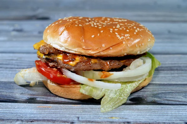 A juicy thick double beef patty with cheese covered with sauce, crispy lettuce, fresh tomatoes, onions and pickles in a large sesame seed bun, a beef burger hamburger sandwich with special sauces