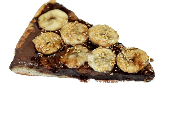 A sweet baked pastry of chocolate pizza that baked in the oven then covered with melting chocolate and topped with slices of fresh banana fruit and sesame seeds, a chocolate pie sweet dessert