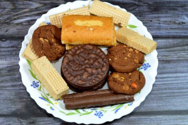 Çikolata çubuklu bir şeker tabağı, çikolata kremalı çıtır gofretler vanilyalı gevrek bisküviler, çilekli kremalı İsviçre dürümü, çikolatalı kurabiyeler.