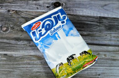 Kahire, Mısır, 11 Ağustos 2023: Belhana tam kremalı inek sütü paketi Mansour şirketi tarafından 450 mL, tahtadan arka planda izole edilmiş doğal sütün seçici odak noktası, Bel Hana süt ürünü