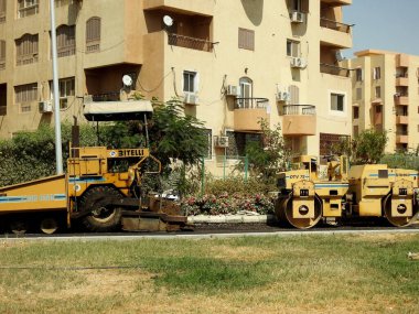 Kahire, Mısır, 21 Temmuz 2023: Asfalt kaldırım kamyonları ve sıkıştırıcılar, bir kaldırım taşı (Road Paver finisher, asfalt kaldırım makinesi) asfalt beton döşemek için kullanılan bir yapı malzemesidir.