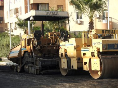 Kahire, Mısır, 19 Temmuz 2023: Asfalt kaldırım kamyonları ve sıkıştırıcılar, bir kaldırım taşı (Road Paver finisher, asfalt kaldırım makinesi) asfalt beton döşemek için kullanılan bir yapı malzemesidir.