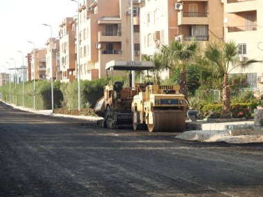 Kahire, Mısır, 19 Temmuz 2023: Asfalt kaldırım kamyonları ve sıkıştırıcılar, bir kaldırım taşı (Road Paver finisher, asfalt kaldırım makinesi) asfalt beton döşemek için kullanılan bir yapı malzemesidir.