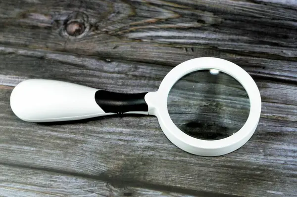A magnifying glass, a convex lens that is used to produce a magnified image of an object, The lens is mounted in a frame with a handle, an icon of detective fiction, can be used to focus light