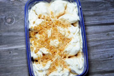 Karamel soslu zengin vanilyalı karamelli dondurma ve üzerine karamelli fındık parçaları, dondurulmuş ve servis edilmeye hazır, yaz zamanı ve tatil konsepti, ferahlatıcı ve eğlenceli, seçici odaklanma.