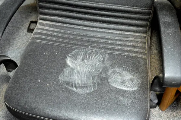 footwear impression shoe print left on a leather chair, dirty dusty shoes print on a dusty chair, tracing, track, foot steps mark, tracking and crime scene concept, forensic detail, selective focus