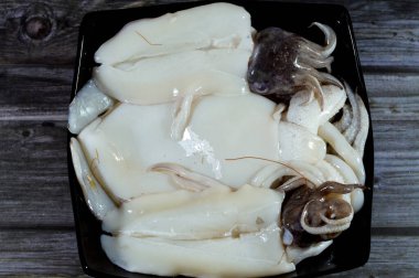 Pişmemiş taze mürekkep balığı, uzamış yumuşak gövdeli yumuşakça, büyük gözler, sekiz kol ve süper düzen Decapodiformes 'taki iki dokunaç mürekkep balığı kamuflaj ve sinyal için renk değiştirebilir.