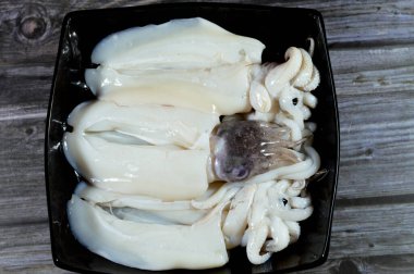 Pişmemiş taze mürekkep balığı, uzamış yumuşak gövdeli yumuşakça, büyük gözler, sekiz kol ve süper düzen Decapodiformes 'taki iki dokunaç mürekkep balığı kamuflaj ve sinyal için renk değiştirebilir.