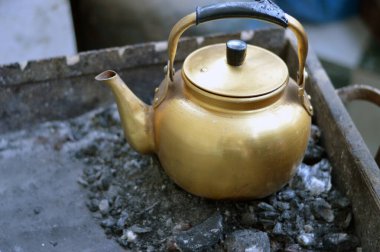 Çay yapmak için kaynayana kadar kömürün üstünde olan eski bir antika çaydanlık, siyah çay yapmak için geleneksel bir yöntem, seçici bir odaklanma.