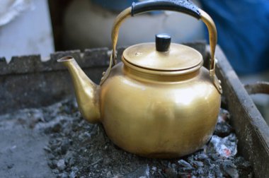 Çay yapmak için kaynayana kadar kömürün üstünde olan eski bir antika çaydanlık, siyah çay yapmak için geleneksel bir yöntem, seçici bir odaklanma.