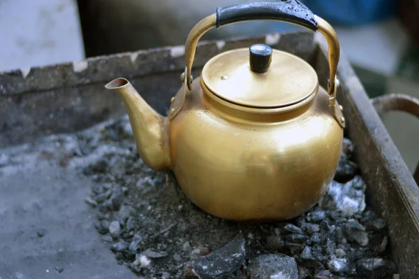 Çay yapmak için kaynayana kadar kömürün üstünde olan eski bir antika çaydanlık, siyah çay yapmak için geleneksel bir yöntem, seçici bir odaklanma.
