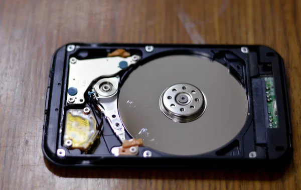 Laptop 2.5 inch hard disk drive storage memory, repair broken computer part, a close up view of an open hard disc with platters, spindle, actuator and read, write head, a detailed view inside HDD