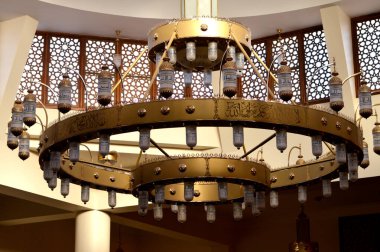 Büyük, dairesel bir cami avizesi lambalı, bakır ve diğer metallerden yapılmış, caminin içindeki büyük cami kubbesine sabitlenmiş, caminin ana aydınlatmasını sağlayan bir tavan lambası.