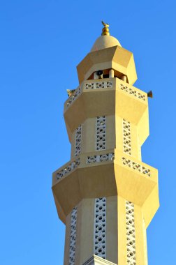 Mavi gökyüzü, minare ya da kuleye karşı bir caminin altın süslemesi olan uzun bir minare. Cennet, İslam dini ve mimari konsepti, cami direğinin seçici odak noktası.