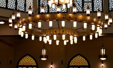 Büyük, dairesel bir cami avizesi lambalı, bakır ve diğer metallerden yapılmış, caminin içindeki büyük cami kubbesine sabitlenmiş, caminin ana aydınlatmasını sağlayan bir tavan lambası.